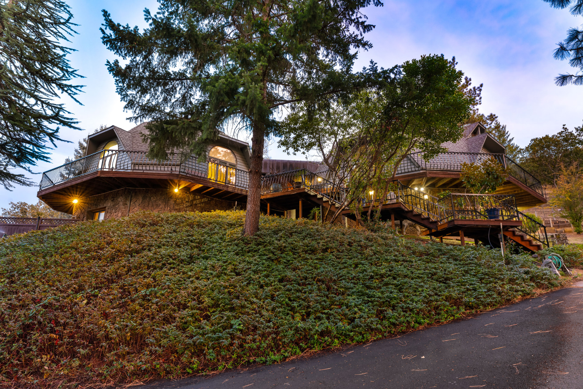 The hillside residence at twilight, showing both connected domes and the wraparound decks