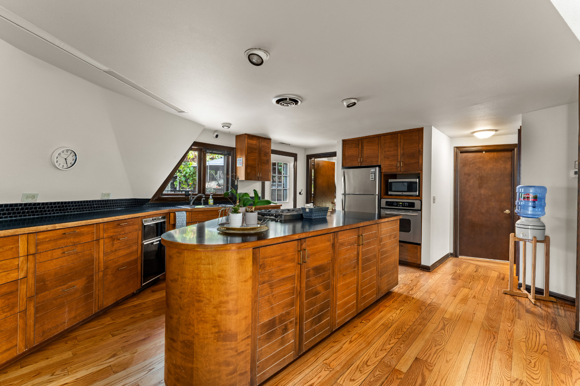 Main kitchen with extensive wood cabinetry, hardwood floors, and a curved island